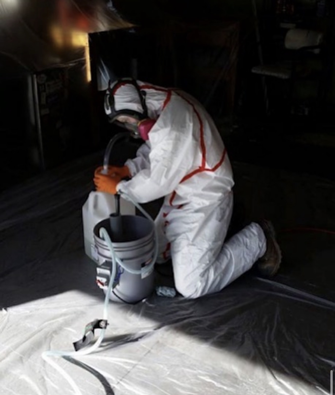 Technician in full PPE mixing eco-friendly odor-eliminating solution on site.